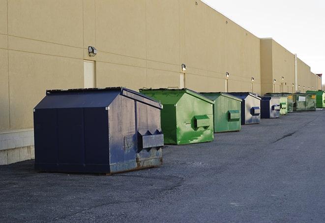 construction workers toss wood scraps into a dumpster in Benton